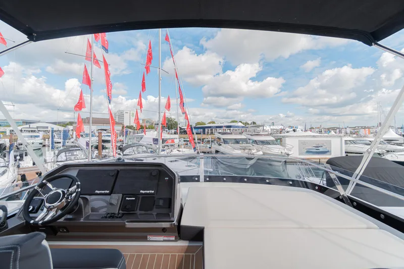 Allouise Yacht Photos Pics Flybridge view of 2022 Galeon 460 Fly yacht at marina with red flags and cloudy sky.