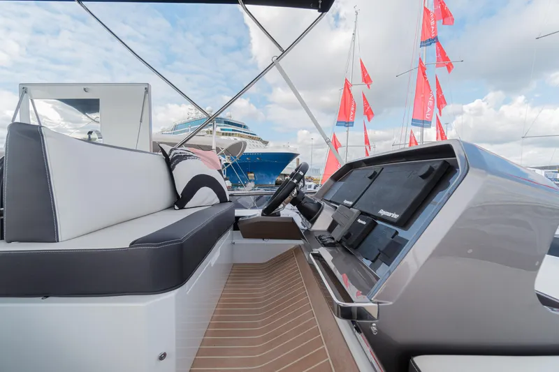 Allouise Yacht Photos Pics 2022 Galeon 460 Fly yacht cockpit with modern controls and seating, docked with flags in background.
