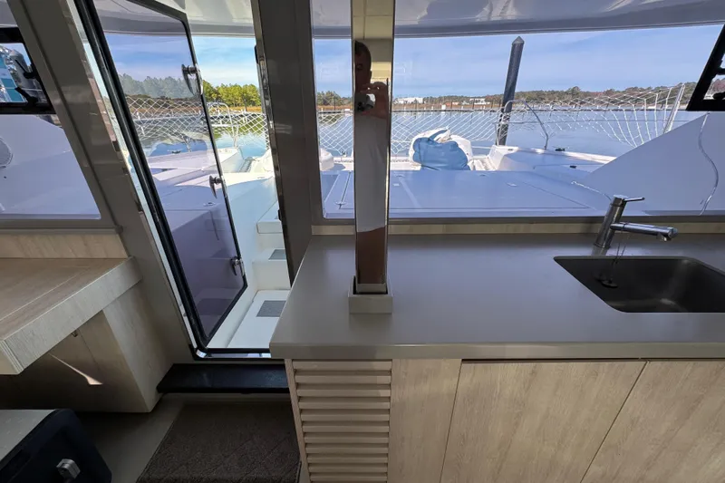 Daylight Yacht Photos Pics Interior view of 2018 Leopard 40 catamaran kitchen with sink and outdoor deck access.