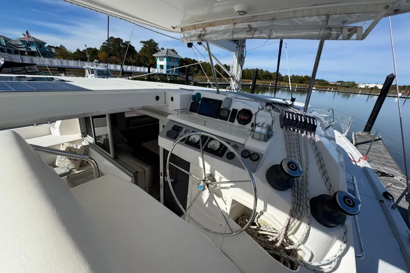 Daylight Yacht Photos Pics 2018 Leopard 40 catamaran cockpit with steering wheel, control panel, and ropes, docked by calm waters.