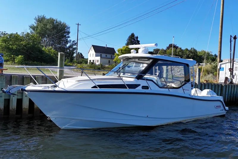  Yacht Photos Pics 2023 Boston Whaler 325 Conquest boat docked by a scenic shoreline.