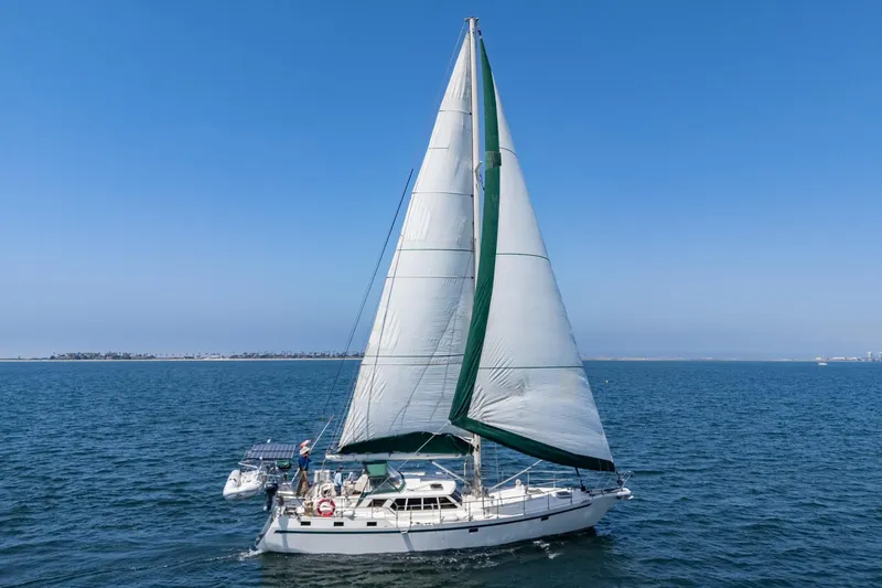 Aesclepius Yacht Photos Pics 50' steel pilothouse cruising on open sea under clear blue sky.