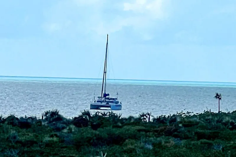 Miss Roxy Yacht Photos Pics Sailboat Dolphin 460, 2006 model, on calm ocean near lush green coastline.