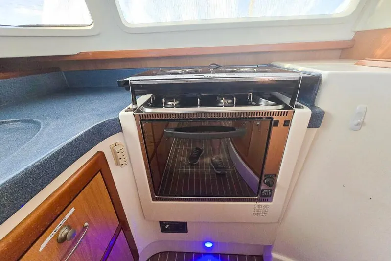 Miss Roxy Yacht Photos Pics Compact kitchen area in a 2006 Dolphin 460 yacht with built-in oven and stove.