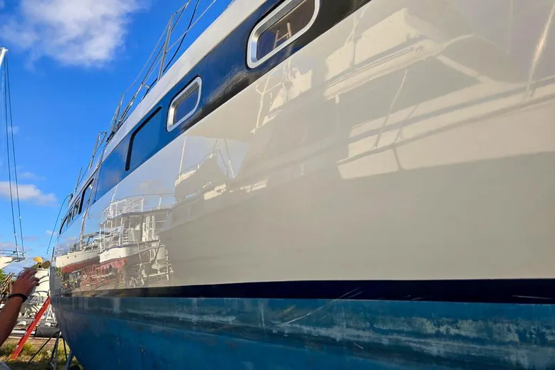 Miss Roxy Yacht Photos Pics Polished hull of a 2006 Dolphin 460 sailboat reflecting nearby boats under a clear blue sky.