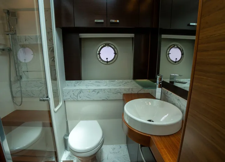 True North Yacht Photos Pics Luxurious bathroom in 2017 Tiara Yachts F53 Flybridge with modern fixtures and porthole window.