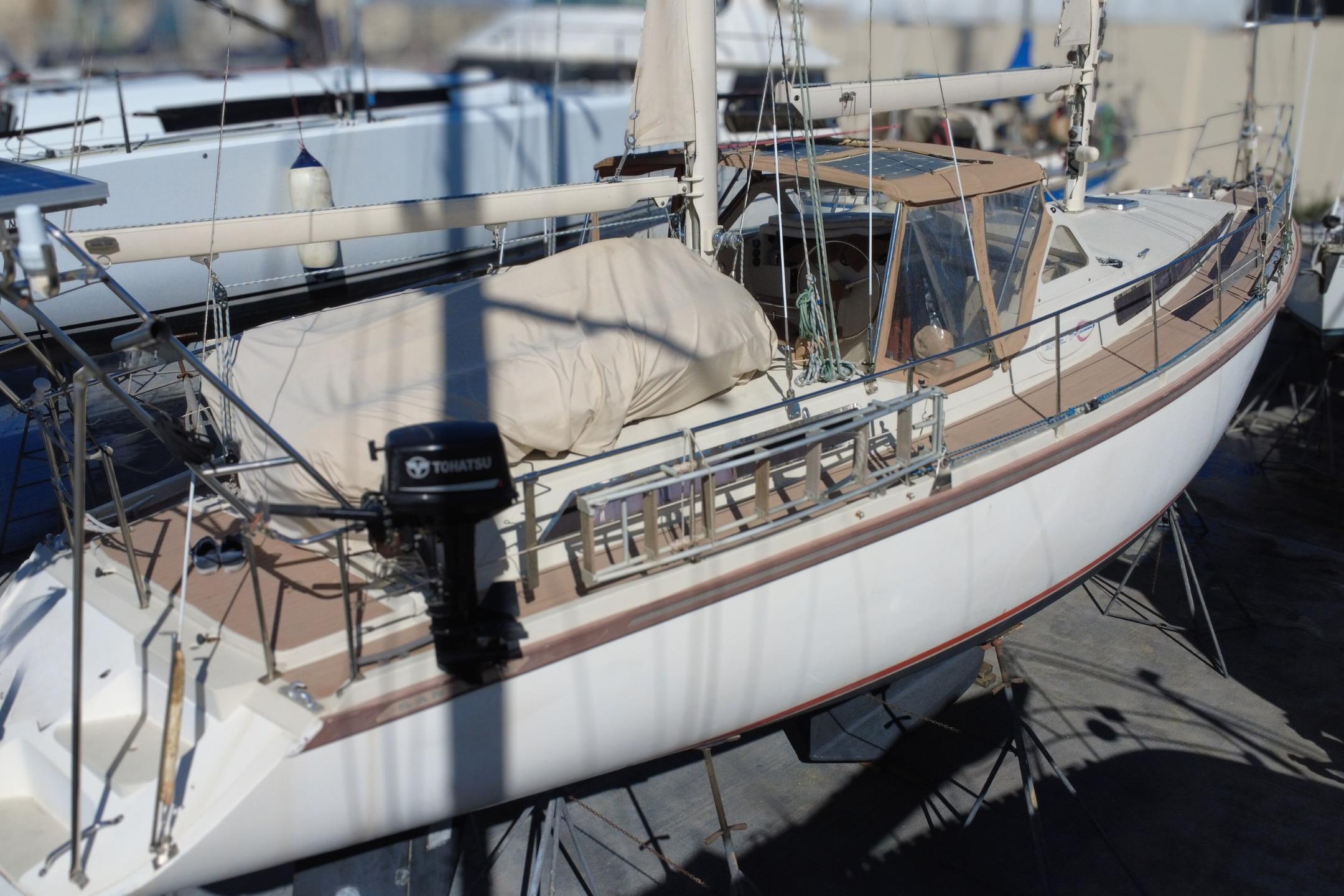 1995 Amel Santorin 46 sailboat on stands, featuring a covered deck and outboard motor.