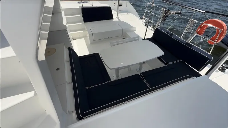 Ivana V Yacht Photos Pics Outdoor seating area on a 2012 Lagoon 450 catamaran with navy cushions and white tables.
