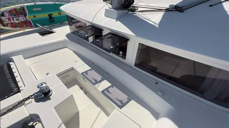 Ivana V Yacht Photos Pics 2012 Lagoon 450 yacht deck with storage compartments and winch, docked near a colorful paddleboard.