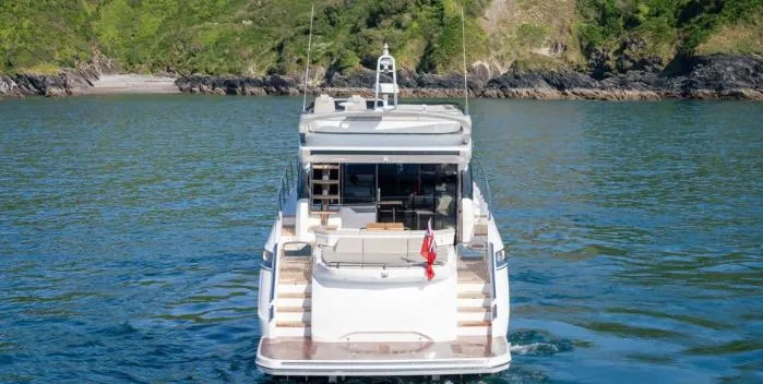  Yacht Photos Pics 2025 Princess S62 yacht on serene water with lush green cliffs in the background.