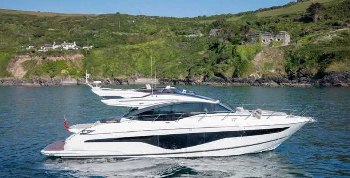  Yacht Photos Pics Luxurious 2025 Princess S62 yacht cruising near lush green coastline.