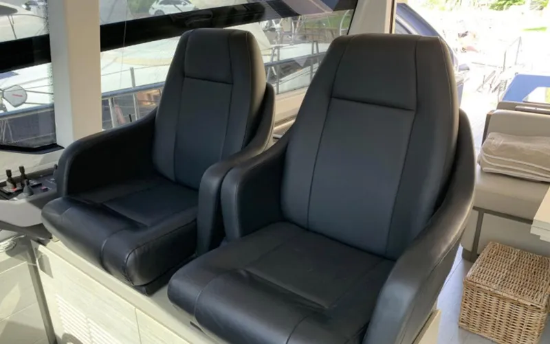  Yacht Photos Pics Luxury seating on a 2020 Pershing 62 yacht, featuring two black leather chairs.