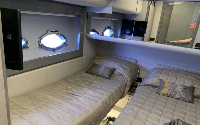  Yacht Photos Pics Luxurious twin cabin interior of 2020 Pershing 62 yacht with modern decor and porthole windows.