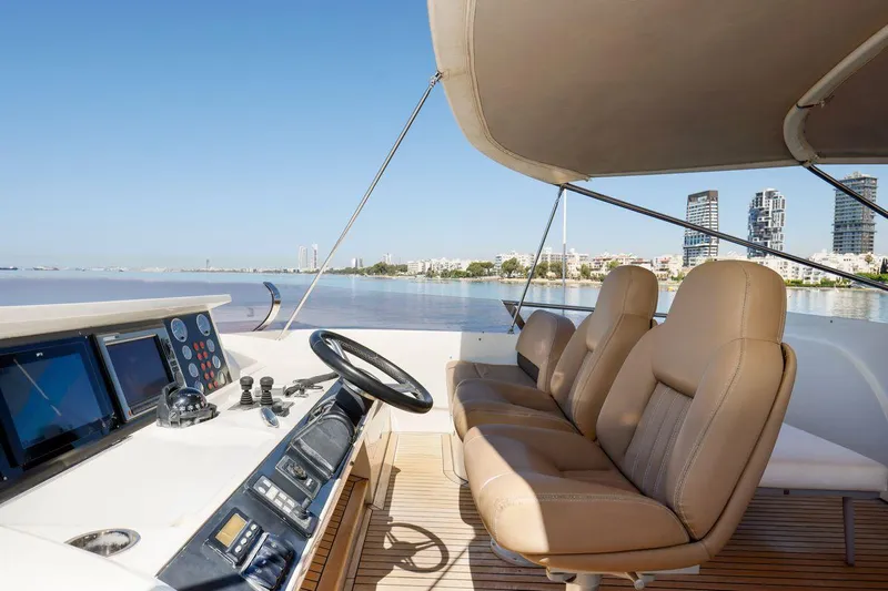  Yacht Photos Pics Flybridge 85 Motor Yacht helm with leather seats, overlooking city skyline and calm waters.
