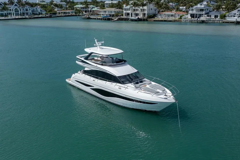  Yacht Photos Pics Luxurious 2026 Princess F65-079 yacht cruising in serene blue waters near coastal homes.