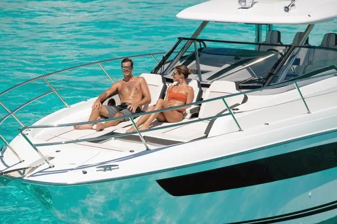  Yacht Photos Pics 2023 Jeanneau Leader 12.5 WA boat with two people relaxing on deck in clear blue water.