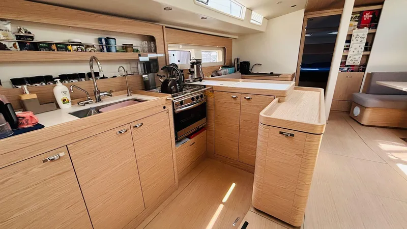  Yacht Photos Pics Modern kitchen interior of 2024 Beneteau Oceanis Yacht 54, featuring sleek wood cabinetry.