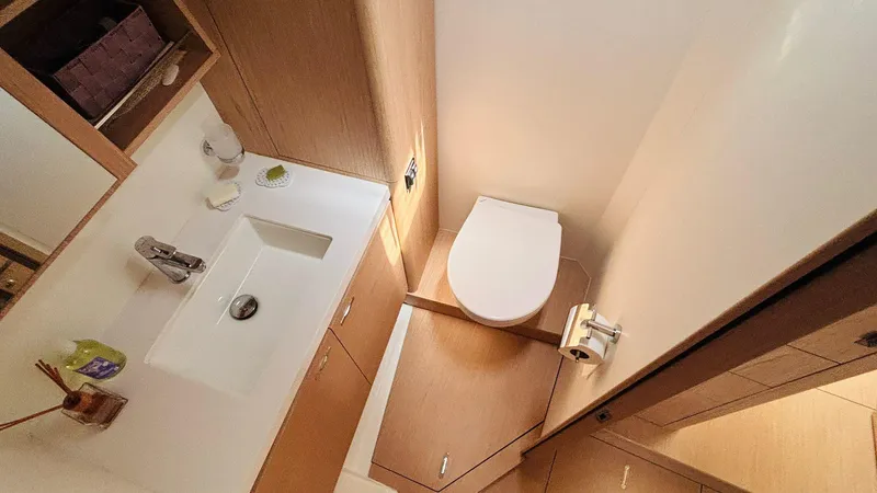  Yacht Photos Pics Luxurious bathroom in 2024 Beneteau Oceanis Yacht 54, featuring modern fixtures and wooden cabinetry.