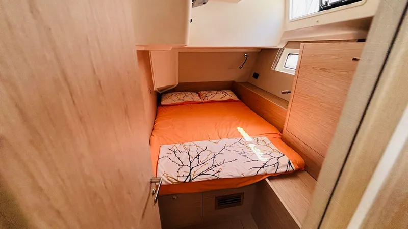  Yacht Photos Pics 2024 Beneteau Oceanis Yacht 54 cabin with orange bedding and wooden interior.