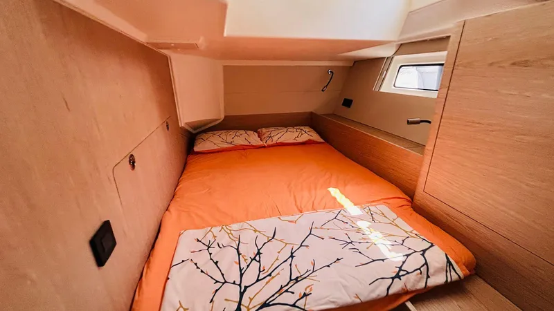  Yacht Photos Pics Cozy cabin interior of 2024 Beneteau Oceanis Yacht 54 with orange bedding and natural light.