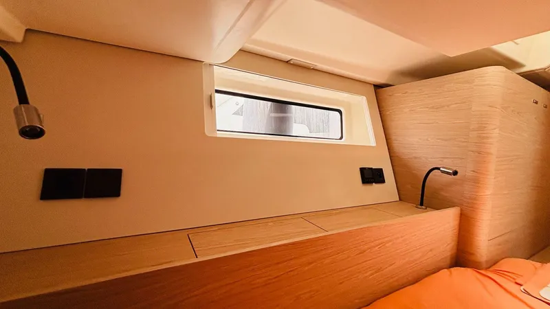  Yacht Photos Pics Interior cabin of 2024 Beneteau Oceanis Yacht 54, featuring modern wood finish and window.