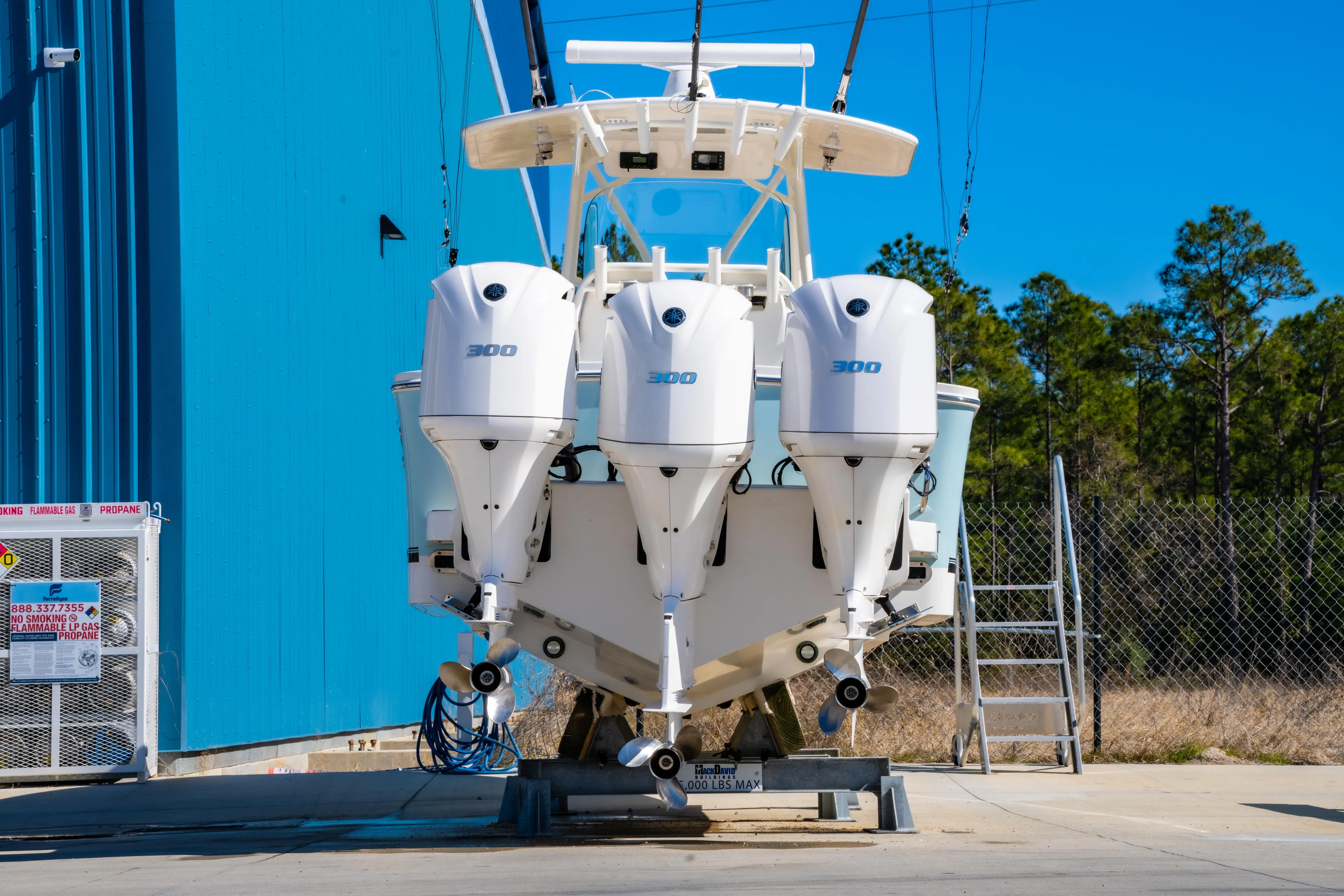  Yacht Photos Pics 2019 Regulator 34 boat with triple outboard engines, parked near a blue building.