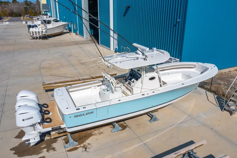  Yacht Photos Pics 2019 Regulator 34 boat with triple Yamaha engines, docked near blue warehouse.