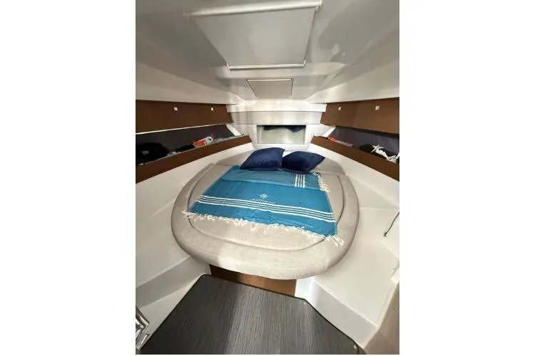  Yacht Photos Pics 2021 Jeanneau NC 895 cabin interior with cozy bed and blue accents.