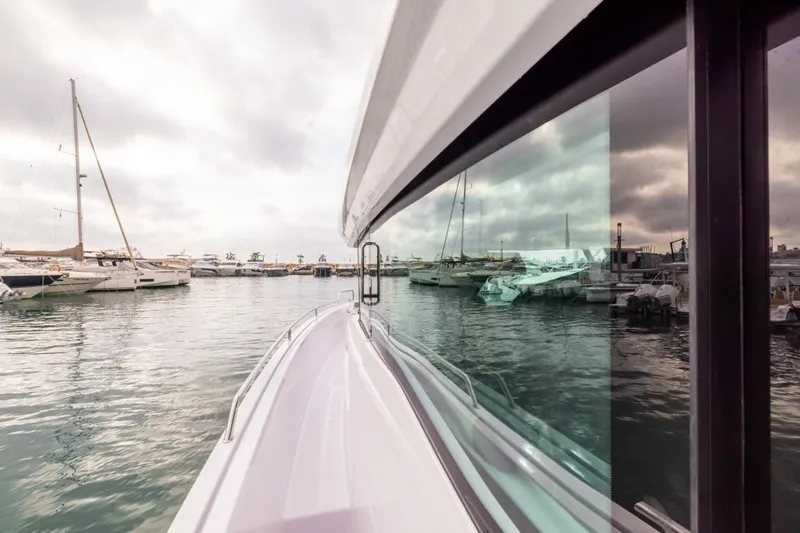  Yacht Photos Pics 2024 Axopar 45 XC Cross Cabin BRABUS Trim docked in a marina, reflecting on water.