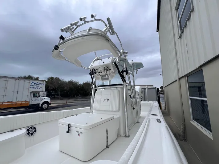  Yacht Photos Pics 2022 Canyon Bay 28h boat with tower, docked near a building under cloudy skies.