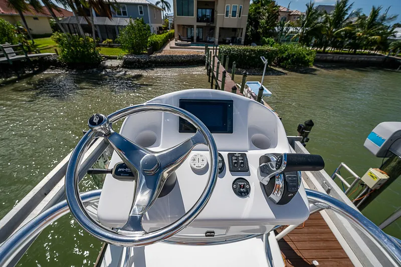  Yacht Photos Pics Canyon Bay 28h 2022 boat helm with steering wheel and controls, docked by waterfront homes.