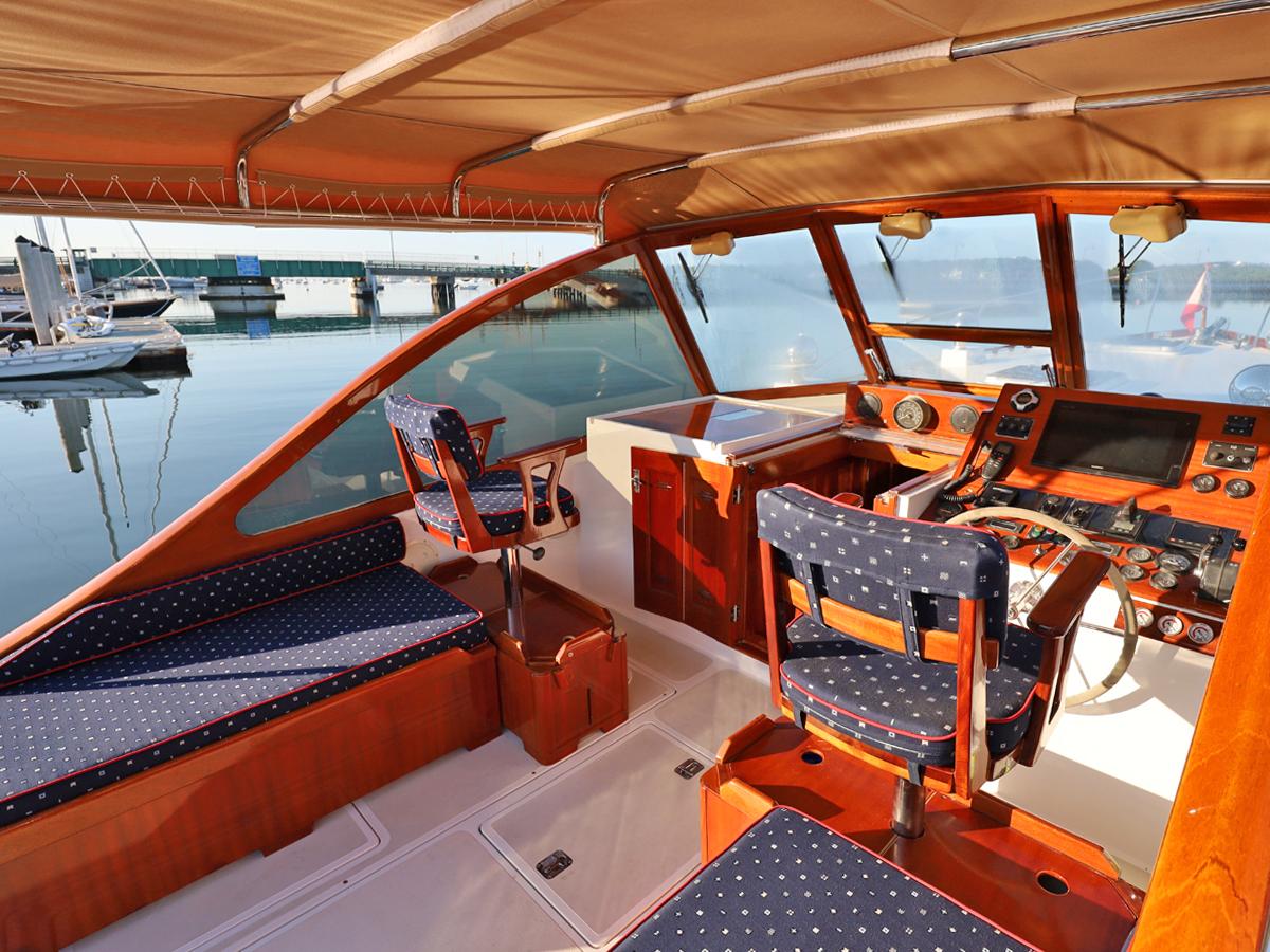 Luxurious 1995 Able 44 yacht interior with polished wood and blue upholstered seating.