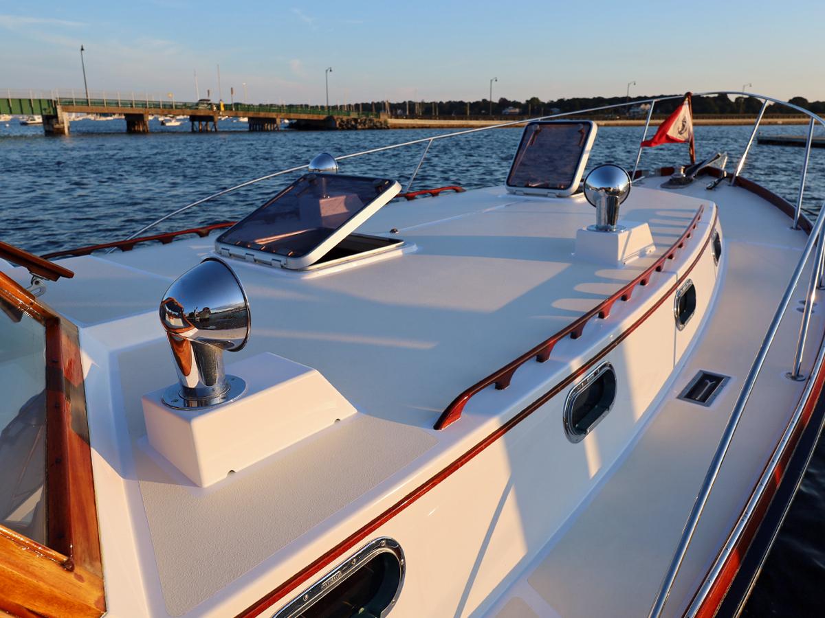 1995 Able 44 boat deck with chrome fixtures, windows, and flag, near a bridge on calm water.