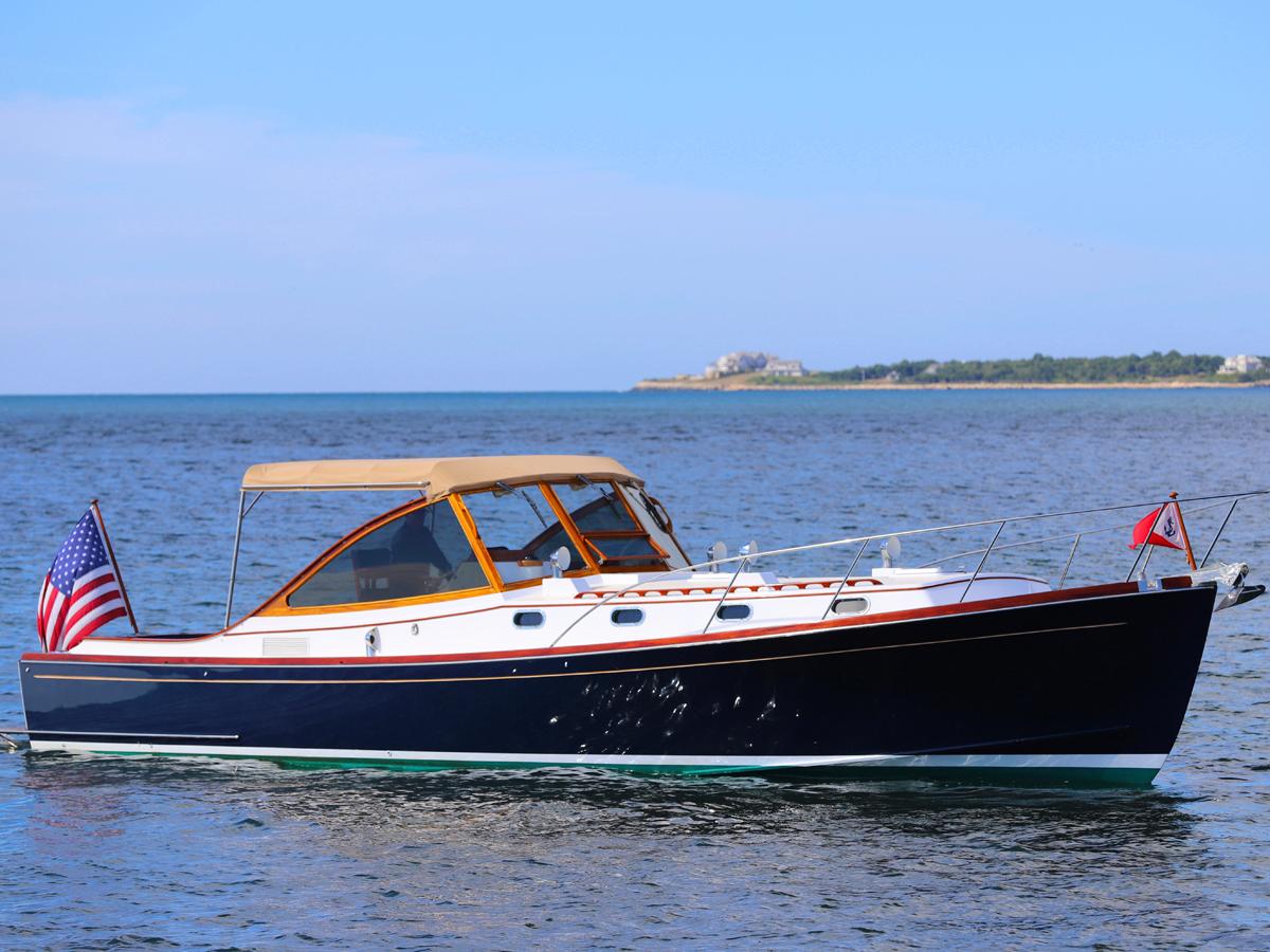 Classic 1995 Able 44 boat on calm water with American flag, clear sky background.