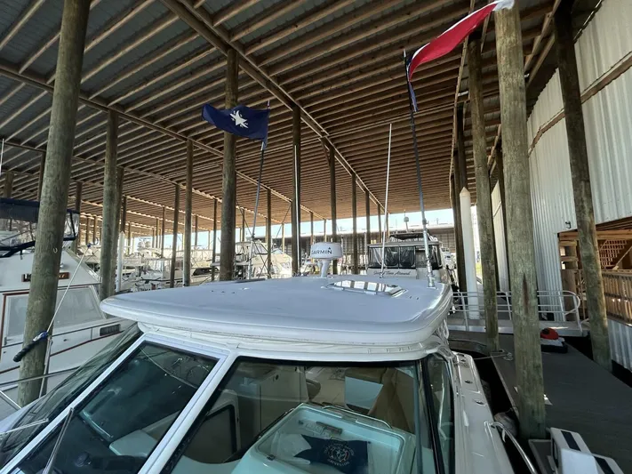 Native Dancer Yacht Photos Pics 2002 Tiara Yachts 3800 Open docked under a covered marina with flags.