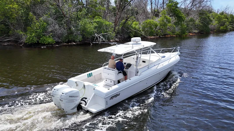  Yacht Photos Pics 2004 Intrepid 348 WA boat cruising on a river with lush green trees.