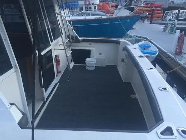 Magna Veritas Yacht Photos Pics 1996 Bayliner 4788 yacht deck with ladder and docked boats in the background.