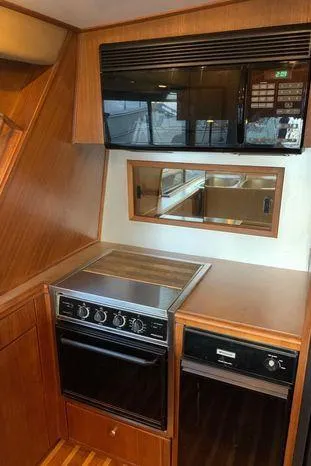 Magna Veritas Yacht Photos Pics 1996 Bayliner 4788 yacht kitchen with stove, microwave, and wooden cabinetry.