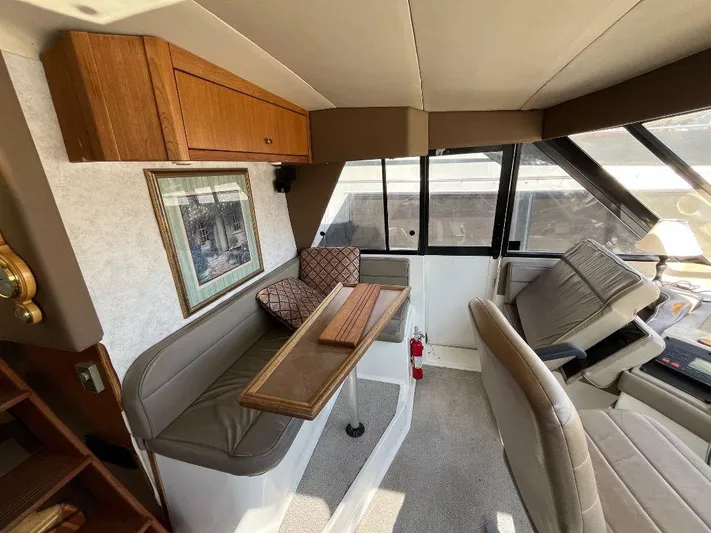 Magna Veritas Yacht Photos Pics Interior of 1996 Bayliner 4788 yacht with seating, table, and helm station.