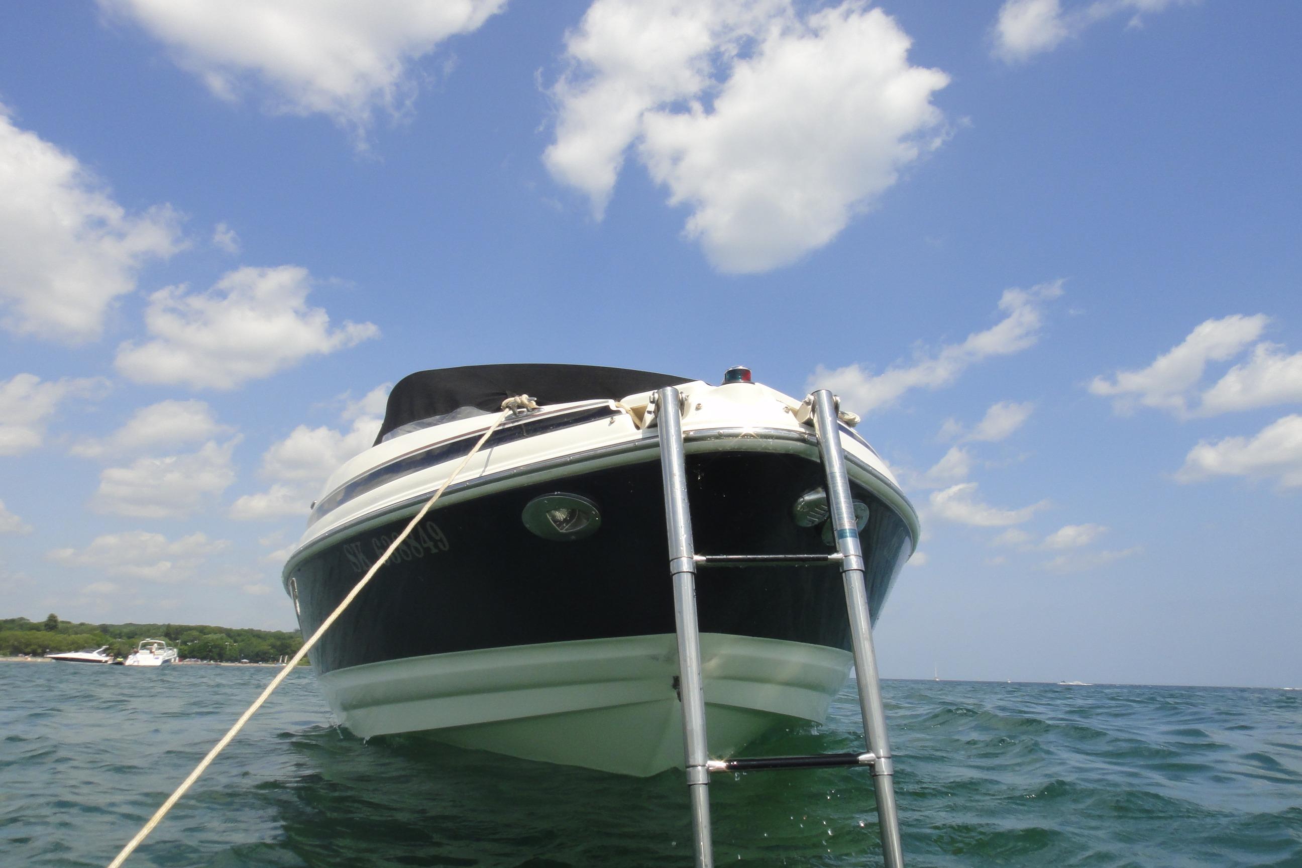 2006 Larson LXi 228 boat on water under blue sky with clouds.