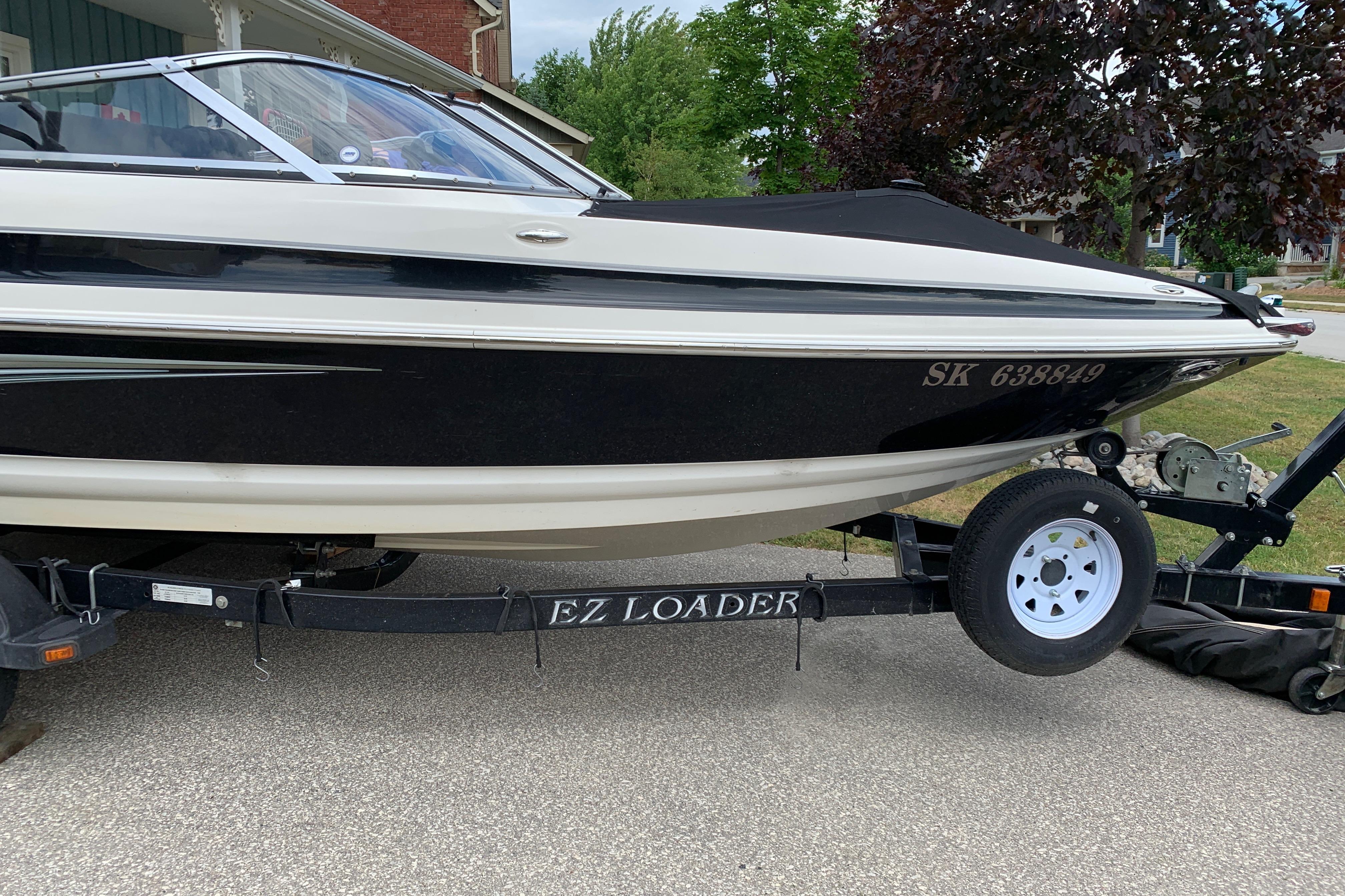 2006 Larson LXi 228 boat on EZ Loader trailer, parked in residential area.