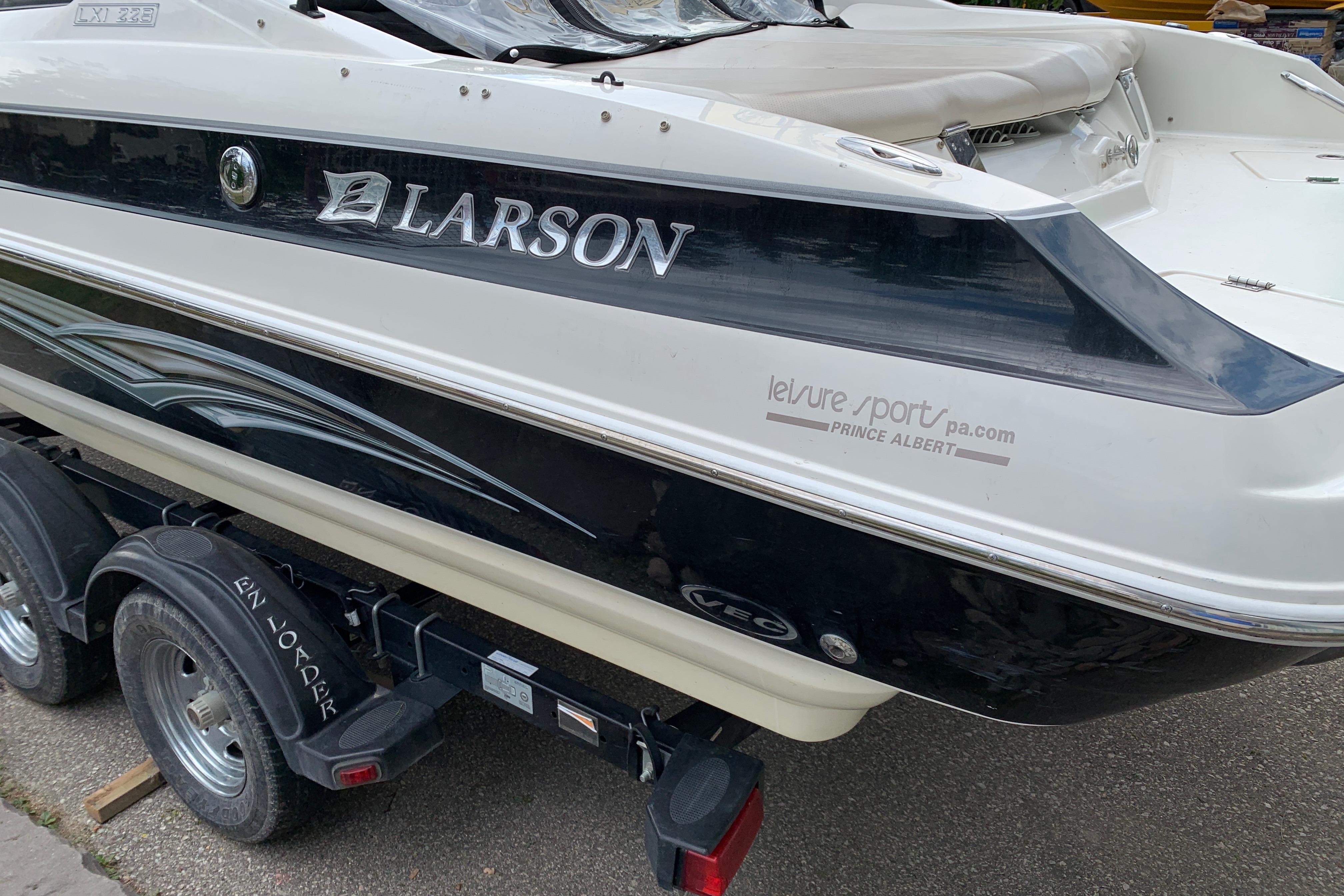 2006 Larson LXi 228 boat on trailer, featuring sleek black and white design.