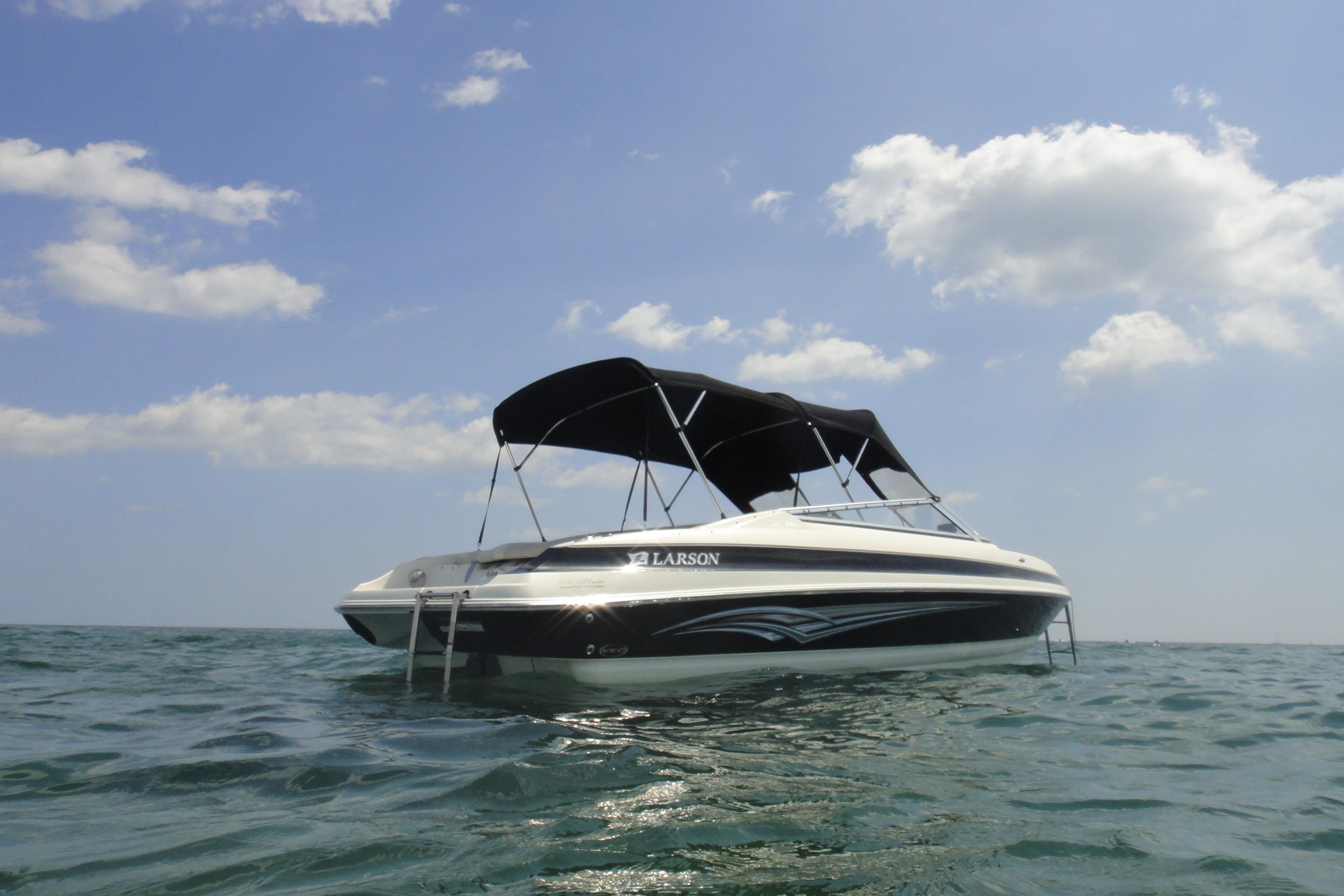 2006 Larson LXi 228 boat floating on calm water under a clear sky.