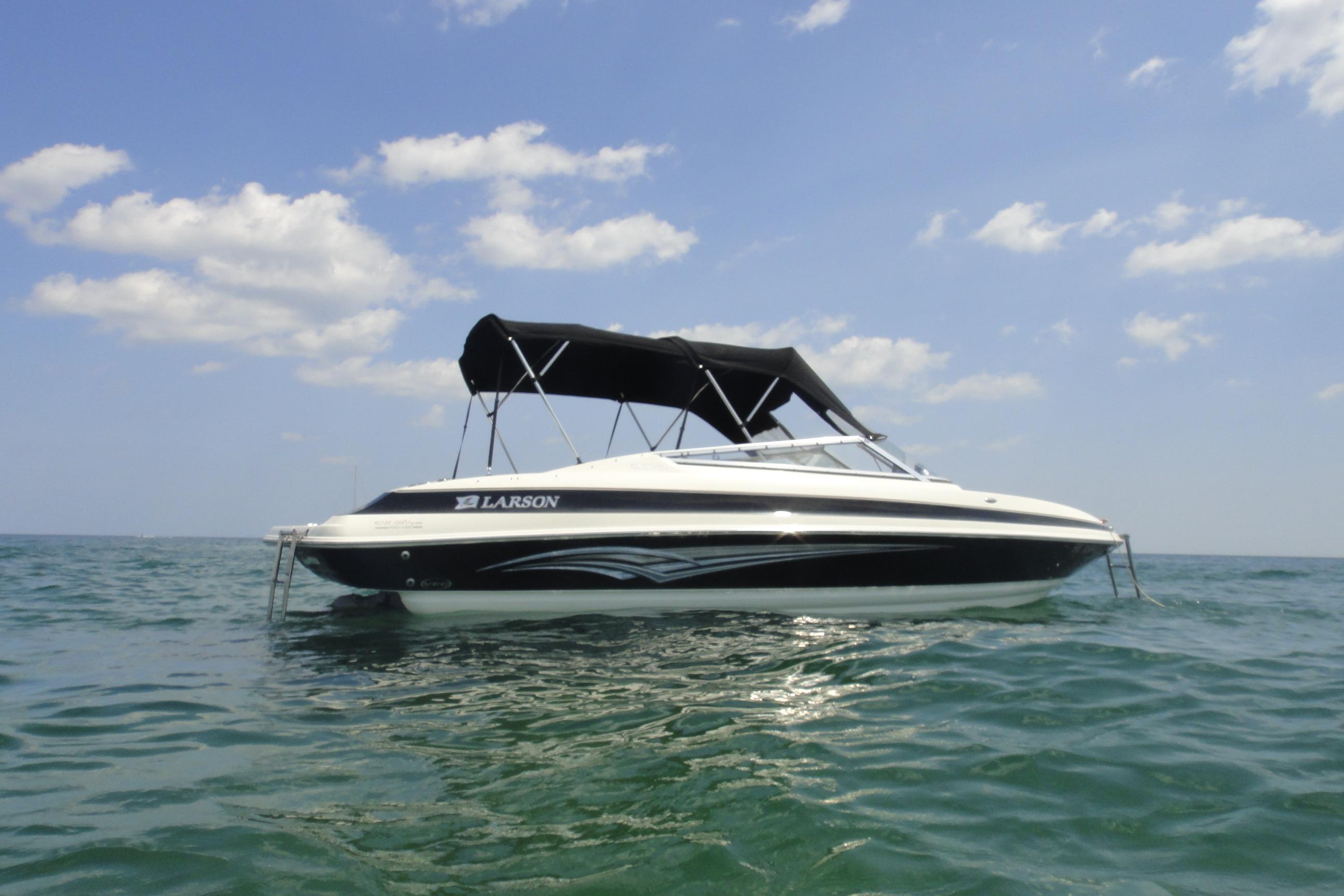 2006 Larson LXi 228 boat on open water under a clear sky.