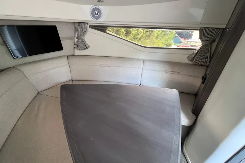 Blu Yacht Photos Pics 2020 Sea Ray Sundancer 320 Outboard cabin interior with seating, table, and window view.