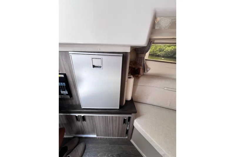 Blu Yacht Photos Pics 2020 Sea Ray Sundancer 320 Outboard interior with compact fridge and seating area.