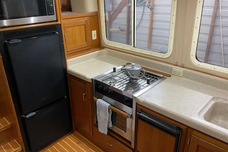 Hot Tuna Yacht Photos Pics Cozy 2002 American Tug kitchen with stove, fridge, and wooden cabinetry.