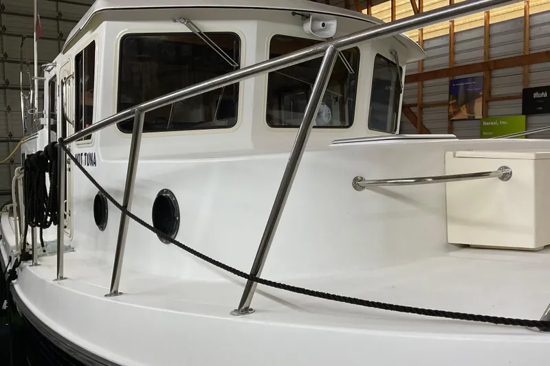 Hot Tuna Yacht Photos Pics 2002 American Tug Hull #24 in a storage facility, showcasing its sleek design and sturdy railings.