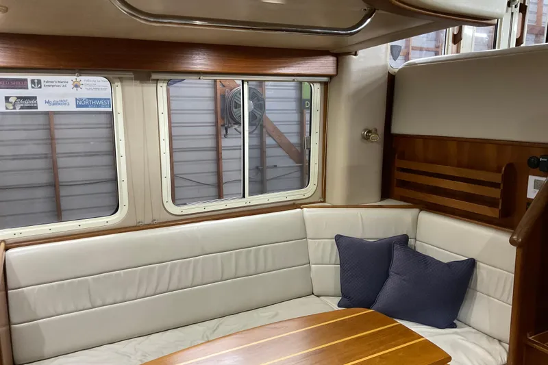 Hot Tuna Yacht Photos Pics Cozy interior of 2002 American Tug Hull #24 with cushioned seating and wooden table.
