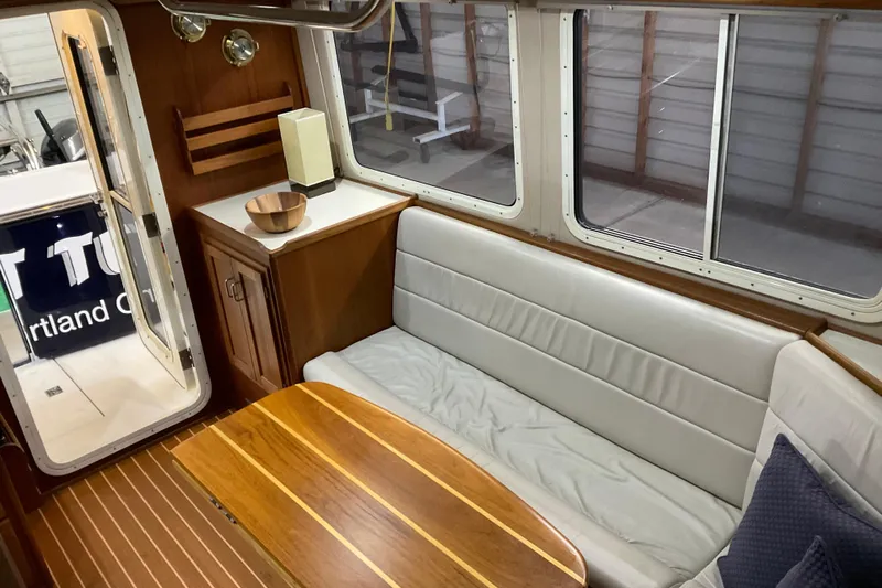 Hot Tuna Yacht Photos Pics Interior of 2002 American Tug Hull #24 with wooden table and cushioned seating.